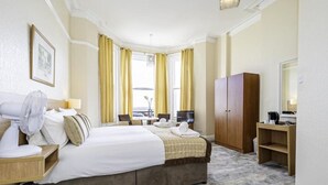 Une chambre d’hôtel comprenant un lit, un bureau, une chaise, une armoire et un téléviseur.