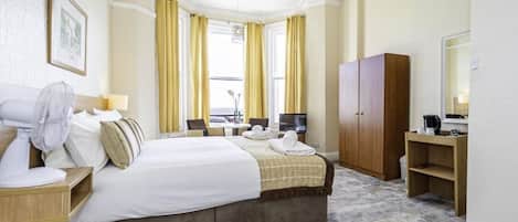 Una habitación de hotel con una cama, un escritorio, una silla, un armario y un televisor.