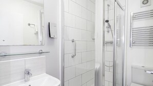A modern bathroom with a glass shower enclosure, a white sink, and a toilet. - Superior Double Room (Eastbourne)