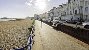 A seaside promenade with a pebble beach, a row of terraced houses, and a pier in the distance. - Superior Double Room (Eastbourne)