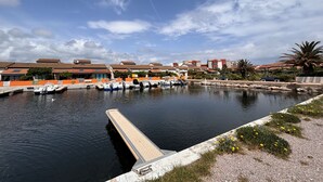 A marina with boats docked, a dock, and residential buildings in the background. - Family apartment with large terrace, swimming pool, parking and wifi fiber (Le Barcarès)