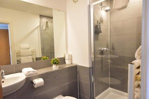 Une salle de bain moderne avec une douche à parois de verre, un lavabo et un miroir.