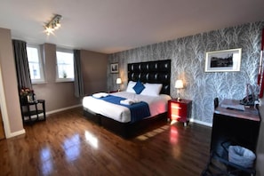 Een hotelkamer met een groot bed, twee nachtkastjes, een bureau en een stoel.