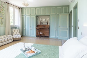 Une chambre comprenant un lit, un bureau, une chaise et un coin repas avec un plateau de nourriture.
