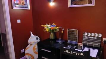 A room with a desk labeled 'DIRECTOR,' a clapperboard, a framed picture of the Titanic, and a Star Wars droid.