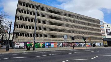 A multi-story building with a flat facade, a street in front, and a traffic light.