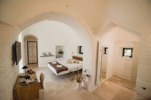 Ein geräumiges Zimmer mit einem Bett, einem Schreibtisch mit Teeausstattung und einer Topfpflanze.