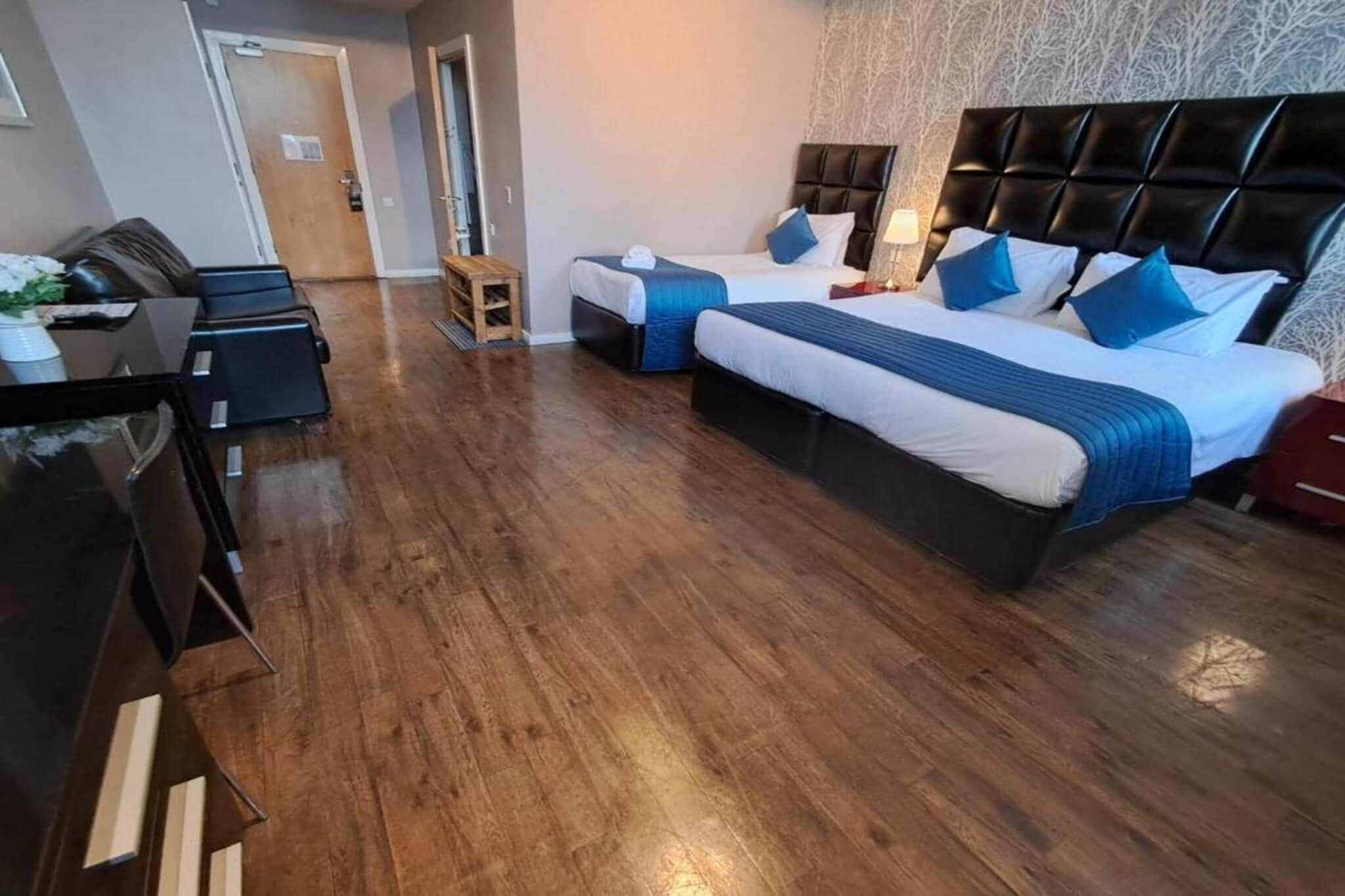 Ein Hotelzimmer mit Holzboden, zwei Betten mit Kopfteilen, einem Schreibtisch und einem Stuhl.