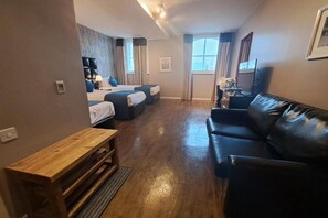 Ein gemütlicher Raum mit Bett, Sofa, kleinem Tisch und Fernseher.