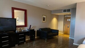 Une chambre d’hôtel équipée d’un téléviseur à écran plat, d’un bureau avec des tiroirs, d’un canapé en cuir noir et d’un lit.