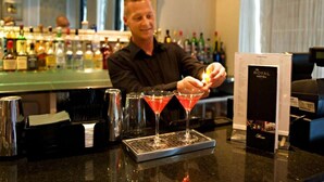 A bartender preparing drinks at a bar with a menu stand and various bottles in the background. - Royal Hotel Cardiff by Belvilla - Standard Double Room - No Window (Cardiff)