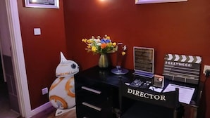 A room with a desk labeled 'DIRECTOR,' a clapperboard, a framed picture of the Titanic, and a Star Wars droid. - Royal Hotel Cardiff by Belvilla - Standard Double Room - No Window (Cardiff)
