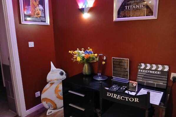 Ett rum med ett skrivbord märkt med texten ”REGISÖR”, en filmklappa, en inramad bild av Titanic och en robot från Star Wars.