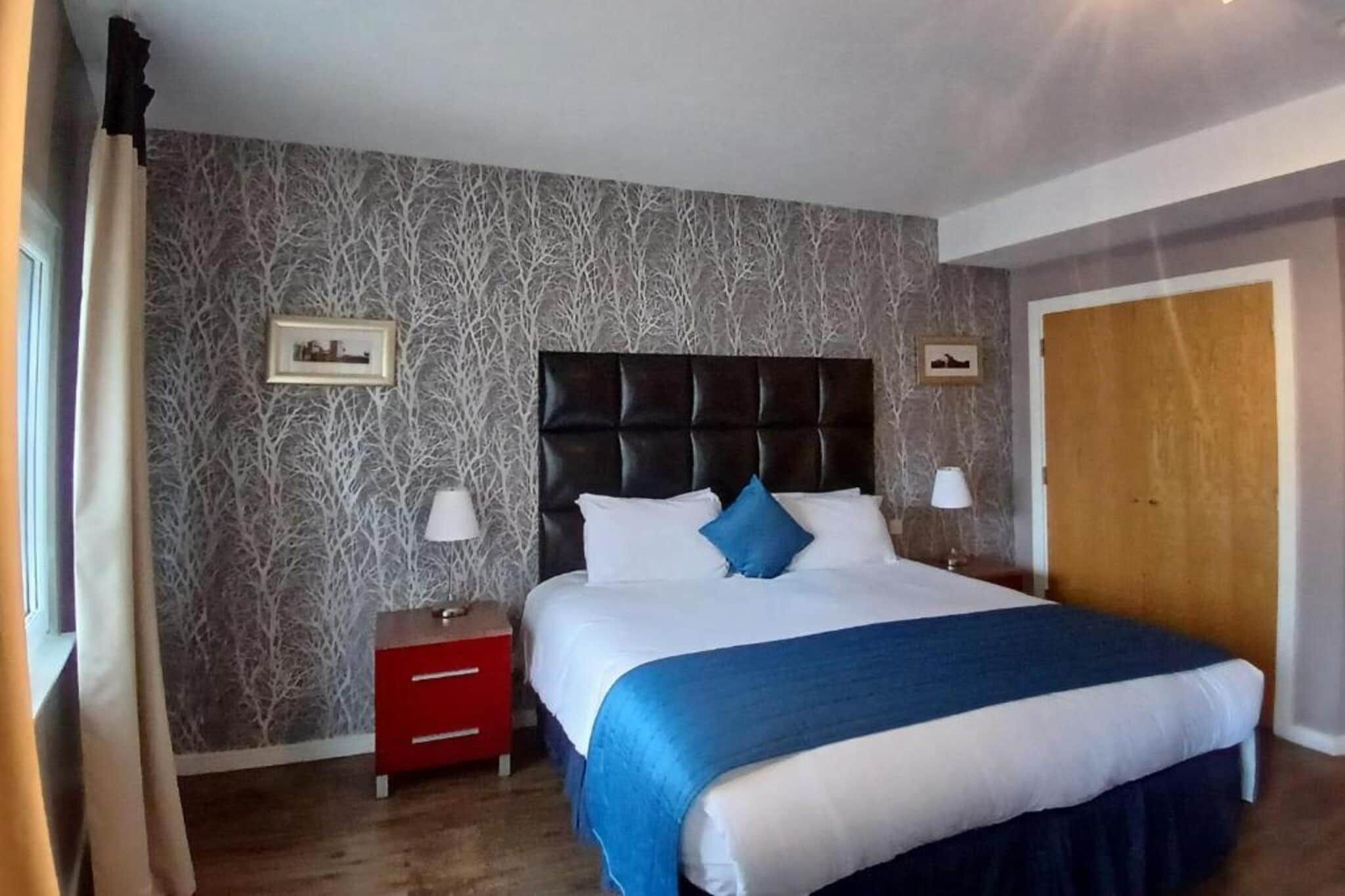 A hotel room with a bed, nightstands, and a wardrobe.