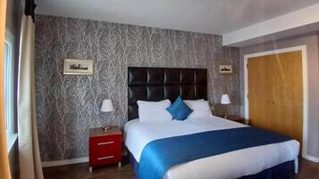 A hotel room with a bed, nightstands, and a wardrobe.