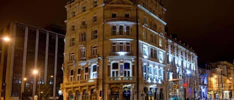 A multi-story building with illuminated windows and a corner entrance.