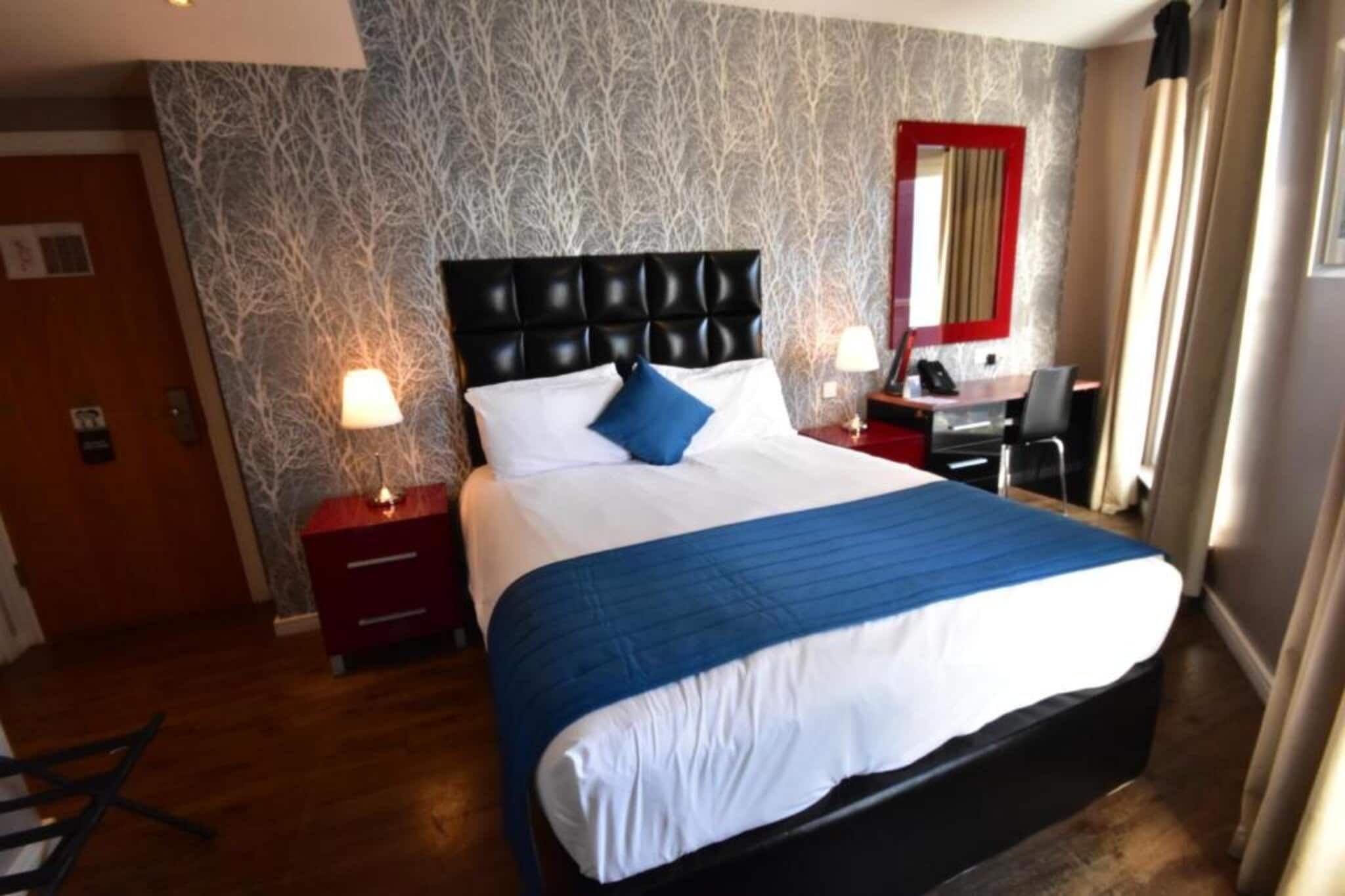 Een hotelkamer met een groot bed, een bureau en een stoel.