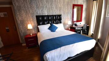 Een hotelkamer met een groot bed, een bureau en een stoel.