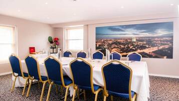 A conference room with a cityscape view, a large window, and a table set for a meeting.