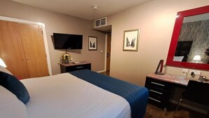Ein Hotelzimmer mit einem Bett, einem Schreibtisch, einem Fernseher und einem Spiegel.