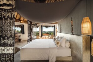 A bedroom with a large bed, a dining area, and a view of the landscape. - Villa Magena (Badung)