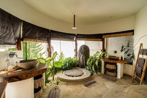 A bathroom with a large stone sink, a wooden vanity, a stone basin, and a statue. - Villa Magena (Badung)