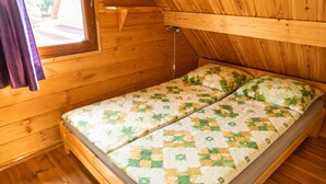 A wooden cabin room with a bed, a window, and a wooden ceiling. - Cottages for 5 People With a Swimming Pool (Kamien Pomorski)