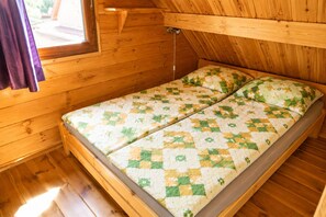Ein Holzhüttenraum mit einem Bett, einem Fenster und einer Holzzieldecke.