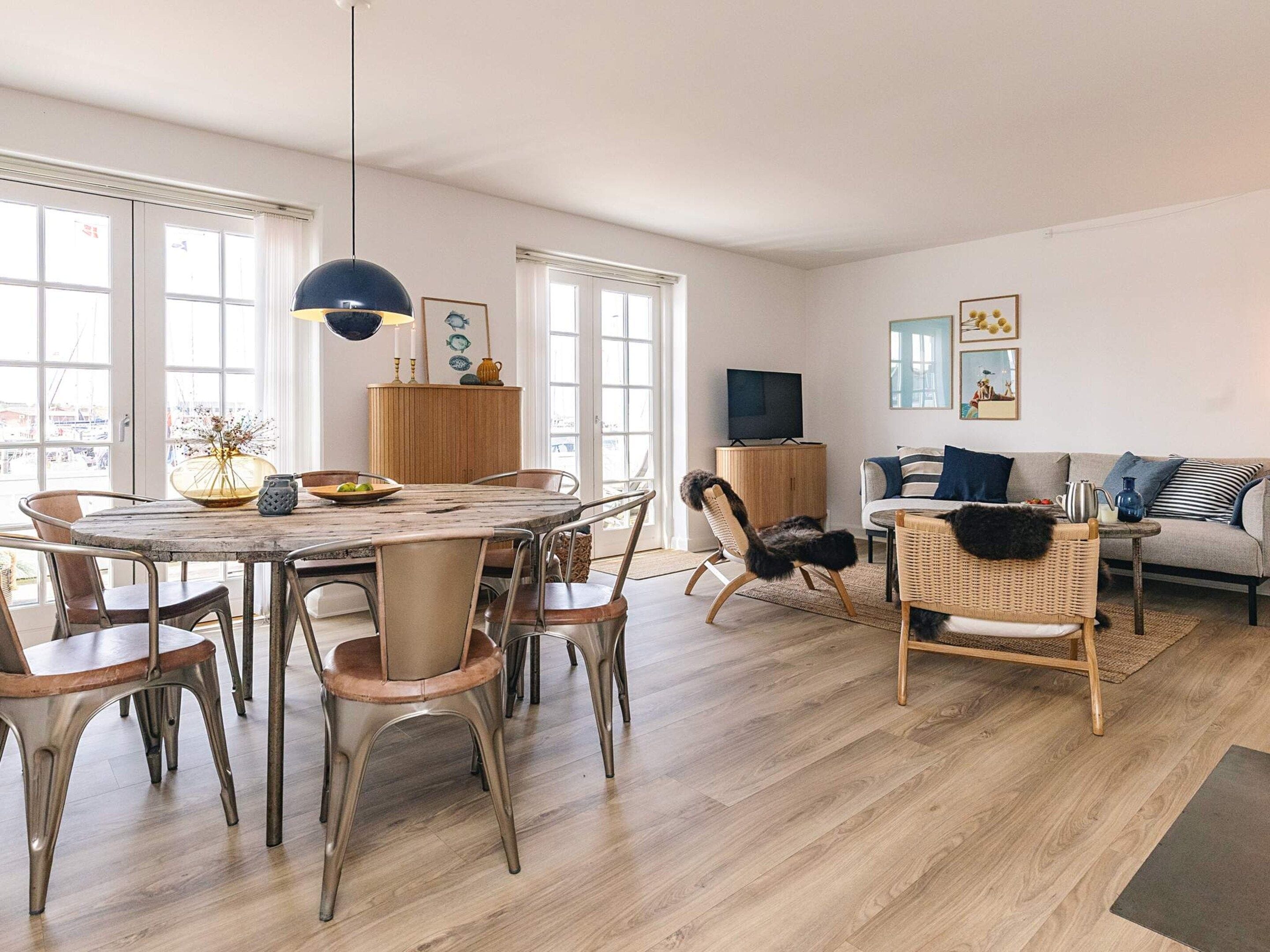 Uma sala de estar moderna com uma mesa de jantar redonda, várias cadeiras, um sofá e uma televisão.