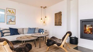 A cozy living room with a sofa, two round tables, a fireplace, and a cat.
