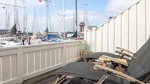 A balcony with a view of a marina, featuring multiple sailboats and a white fence.