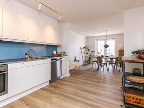 A modern kitchen with white cabinets, stainless steel appliances, and a blue backsplash. - 5 Star Holiday Home in Bagenkop (Sydlangeland)