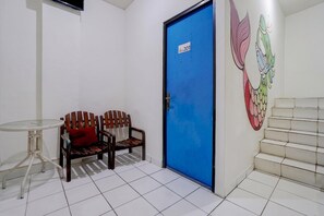 Une pièce avec une porte bleue, une petite table, deux chaises en bois et un escalier.