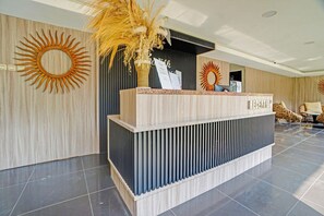 Un comptoir d’accueil au design moderne, une grande décoration solaire sur le mur et un espace d’accueil avec des sièges.
