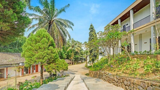 A pathway leading to a building with a stone wall and trees. - Bwalk Hotel Cozy Double (Malang)