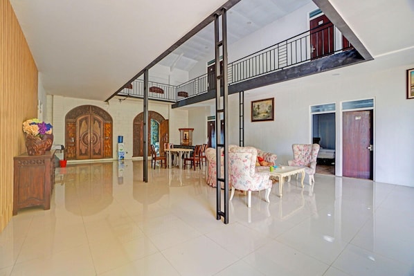Un vaste espace de vie doté d’un haut plafond, d’un escalier et d’un coin repas avec des chaises et une table.