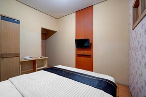 Une chambre d’hôtel avec un lit, une armoire en bois, un téléviseur fixé au mur et un petit bureau avec une chaise.
