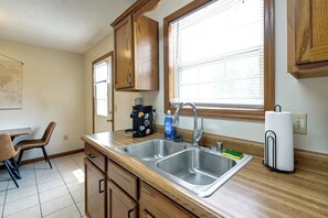 A kitchen with wooden cabinets, a double sink, a window with blinds, and a coffee maker. - Great for Families! Richmond Townhome w/ Patio (Richmond)