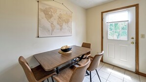 A dining area with a wooden table, four chairs, a world map on the wall, and a door with a window. - Great for Families! Richmond Townhome w/ Patio (Richmond)