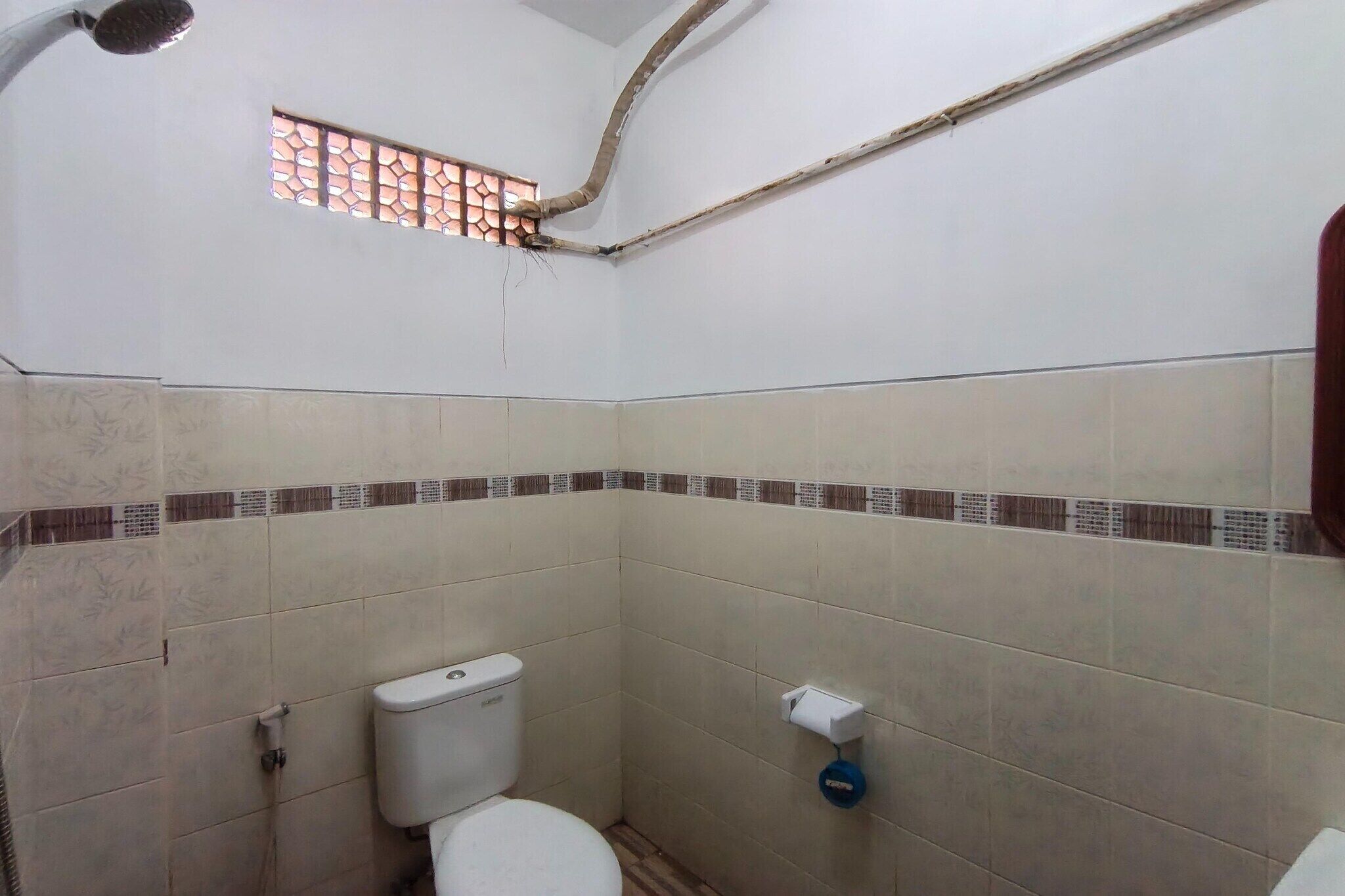 Un baño pequeño con inodoro, ventana y ducha.