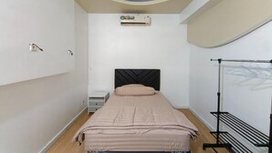 Quarto com cama, ar-condicionado, aquecedor fixado na parede, mesa de cabeceira e varal.