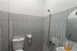 A bathroom with a toilet, a sink, a shower, and a mirror.