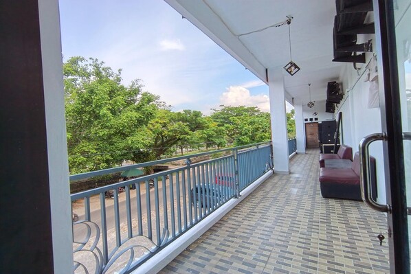A balcony with a tiled floor, a blue railing, and a sofa. - Esun Bue Cozy Single Stay (Palangkaraya)