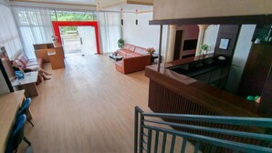 Uma sala de estar ampla com sofá, mesa de centro e televisão. Escada leva a um andar superior.