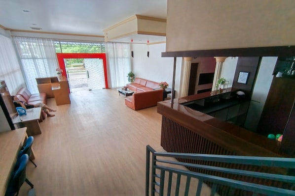 Een ruime woonkamer met een bank, salontafel en televisie. Een trap leidt naar een hoger gelegen verdieping.
