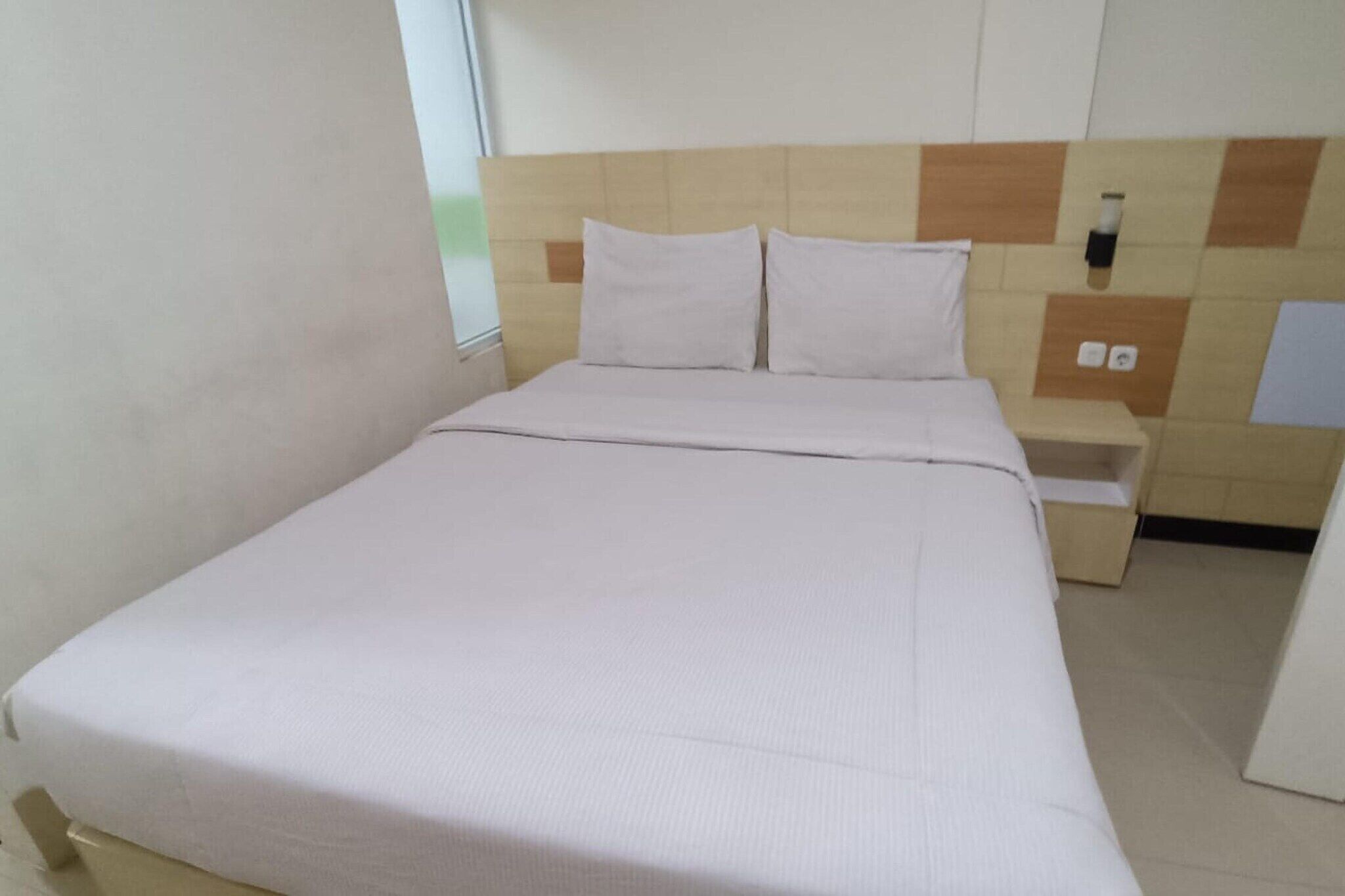 Camera d'albergo con un letto, un comodino e una lampada a parete.