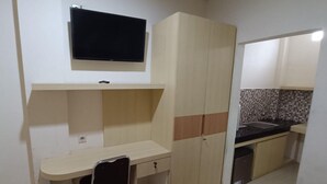Una cocina compacta con televisor, un pequeño comedor y un lavamanos.