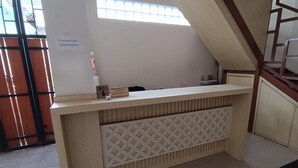Una mesa de recepción con un letrero que indica una red wifi con contraseña, un botón de timbre y una ventana con persianas.
