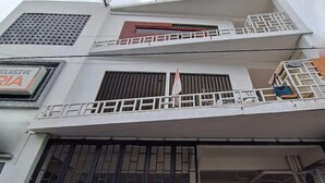 Un edificio de varios pisos con balcones, un letrero que dice 'INCLUSIVE RIA' y una bandera.