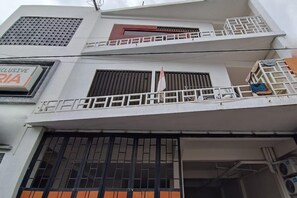 A multi-story building with balconies, a sign for 'INCLUSIVE RIA,' and a flag.